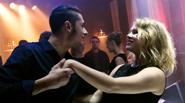 Junger Mann tanzt mit junger Frau im Nachtclub