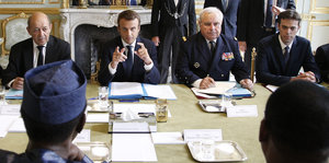 Viele Männer sitzen an einem Verhandlungstisch im Elysée-Palast