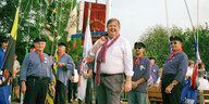 Kandidat Stefan Stader steht lächelnd im Vordergrund. Im Hintergrund Männer mit Mützen und Fischerhemden