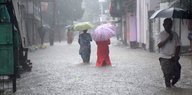 Menschen mit Regenschirm waten durch Wasser