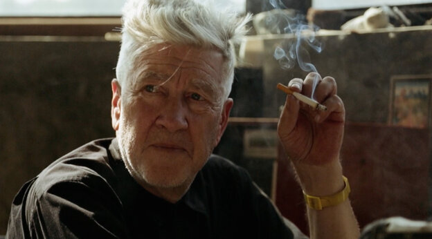 Ein Mann hält eine Zigarette in der Hand. Es ist David Lynch.