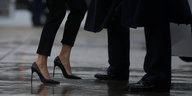 Bildausschnitt: Eine Frau träft hohe Stöckelschuhe, die Person neben ihr trägt flache Schuhe.