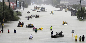 Menschen in Booten auf einer überschwemmten Straße