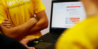 Zwei Menschen in gelben T-Shirts neben einem Laptop, auf dem der Wahl-O-Mat gerade gespielt wird