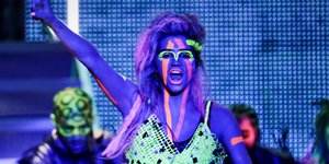 Eine Frau mit neonfarbig leuchtenden Streifen im Gesicht