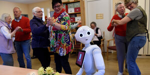 Ein Roboter und mehrere Menschenpaare beim Tanzen