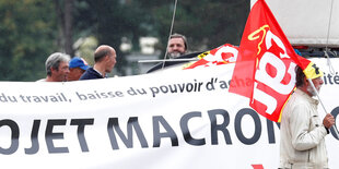 Ein großes Protestbanner, Davor ein Mann mit Fahne