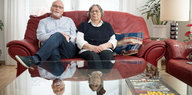 Ein älteres Ehepaar sitzt auf einem roten Sofa