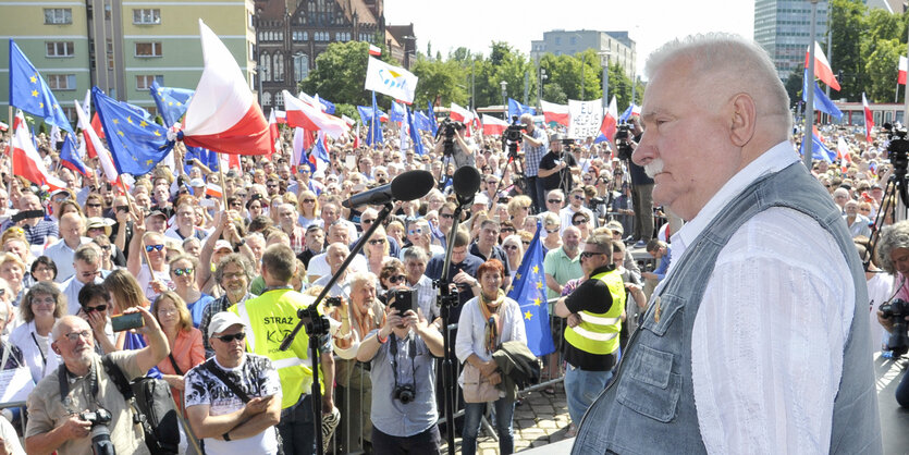 Ein mann in Jeans-Weste auf einer Bühne vor großem Publikum