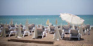 Blick zum Meer über einen Strand mit leeren Liegen