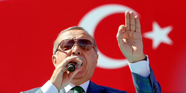 Ein Mann mit Sonnenbriulle vor der türkischen Flagge