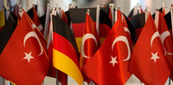 Deutsche und türkische Flaggen stehen auf einem Messestand.