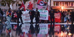 Menschen schwenken Fahnen, davor Polizei