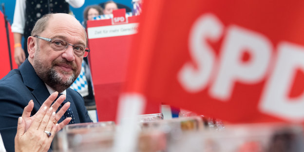 Ein Mann schaut ernst, daneben SPD-Flagge