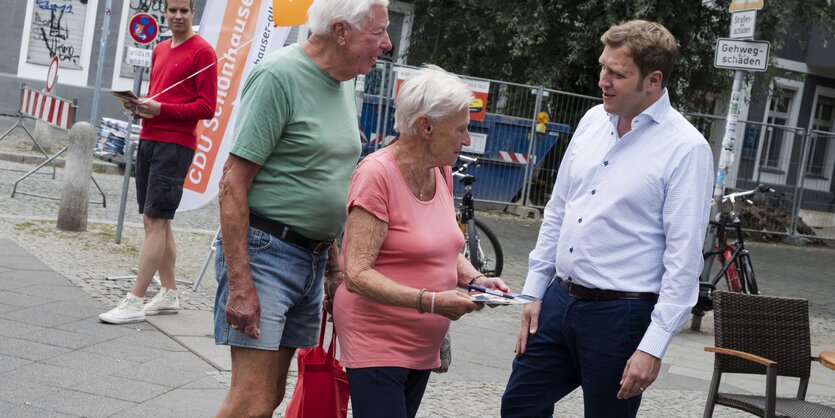 Ein Mann unterhält sich mit einem älteren Ehepaar