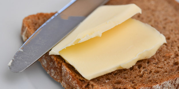 Auf eine Scheibe Brot wird Butter gestrichen