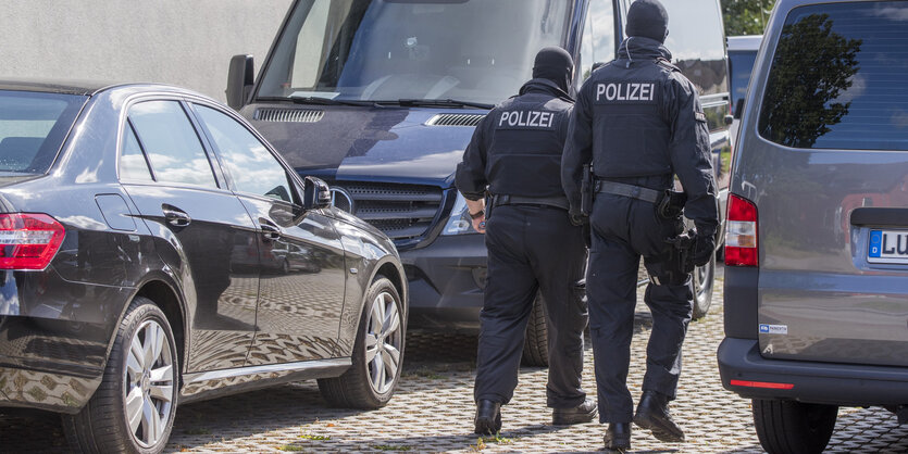 Polizisten einer Spezialeinheit zwischen Fahrzeugen