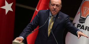 Erdogan steht am Rednerpult und streckt den Arm aus
