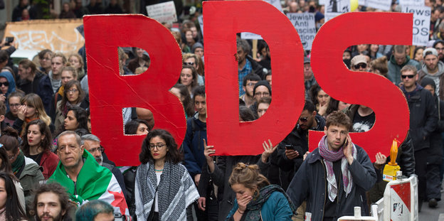 DemonstrantInnen tragen den Schriftzug "BDS"