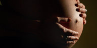 Eine schwangere Frau hält ihre Hände auf ihren Babybauch