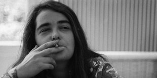 Kate Millett zieht an einer Zigarette und guckt ins Leere