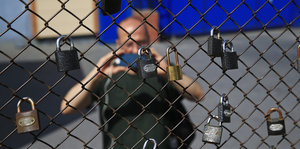 Ein Mann fotografiert einen Zaun mit Schlössern