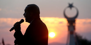 Schatten von Recep Tayyip Erdogan mit Mikrofon vor Sonnenuntergang