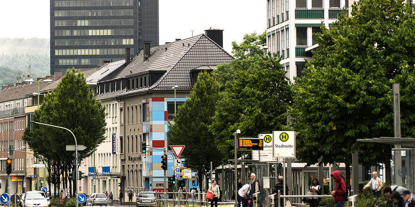 Blick auf eine Häuserzeile mit Bäumen im Vordergrund, im Hintergrund ein Hochhaus