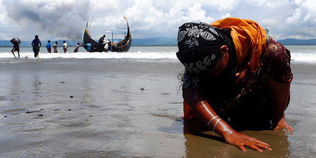 Eine erschöpfte Frau kniet an der Küste auf dem Boden