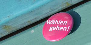 ein rosaner Button mit der Aufschrift „Wählen gehen“ auf grünem Untergrund