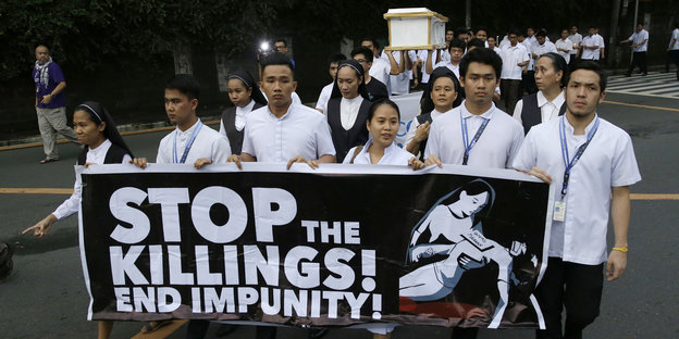 Menschen halten ein Transparent, auf dem „Stop the Killing! End impunity!“ steht