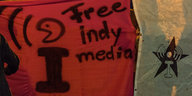 Ein rotes Transparent, auf dem „Free indymedia“ steht