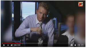 Ein junger Mann mit Krawatte beugt sich nach vorne und guckt in die Kamera