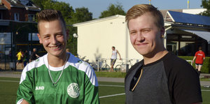 Marino und Fabian stehen lächelnd auf dem Fußballplatz