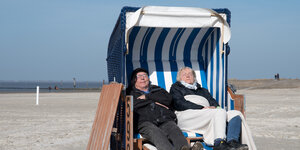 Ein Mann und eine Frau sitzen in einem Strandkorb und dösen in der Sonne