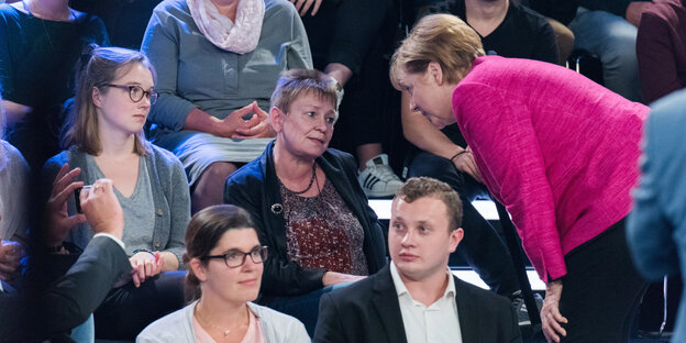 Merkel neigt sich ins Publikum zur Zuschauerin Petra Vogel