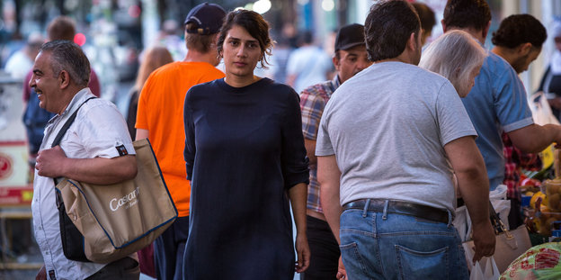 Fatmar Aydemir läuft auf einer Straße an mehreren Menschen vorbei Fatmar Aydemir läuft auf einer Straße an mehreren Menschen vorbei
