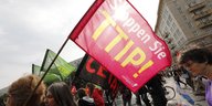 DemonstrantInnen laufen durch eine Stadt und halten eine Fahne hoch auf der steht: "Stoppen Sie TTIP!"