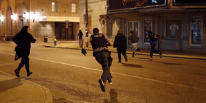 Polizist rennt hinter Protestierenden her