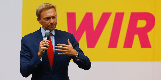 Lindner redet vor einem Schild, auf dem Wir steht