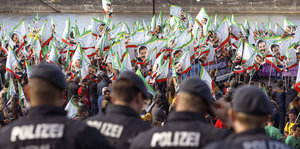 Polizisten stehen vor einer Gruppe Menschen, die Fahnen mit dem Gesicht Öcalans schwenken