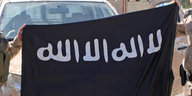 Hände halten eine IS-Fahne hoch