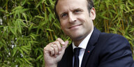Ein Mann, Emmanuel Macron, vor Grünpflanzen