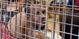 Ein Mann in Unterhand hinter einem Gitter