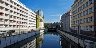 Zwei Wohnböcke, getrennt durch einen Kanal, darüber strahlend blauer Himmel