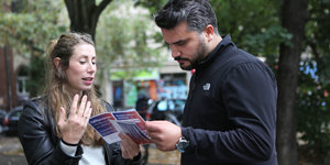Eine Frau zeigt einem Mann Flugblätter und spricht mit ihm