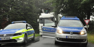 Ein Mann sitzt auf einem LKW und hindert diesen so daran weiterzufahren. Davor ist Polizei zu sehen