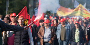 Eine Menschenmenge mit roten Kappen, Transparenten und Feuerwerk