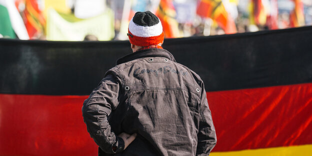 Ein Mann steht vor einer großen Deutschland-Flagge
