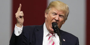 Donald Trump mit erhobenem Zeigefinger steht am Mirkofon